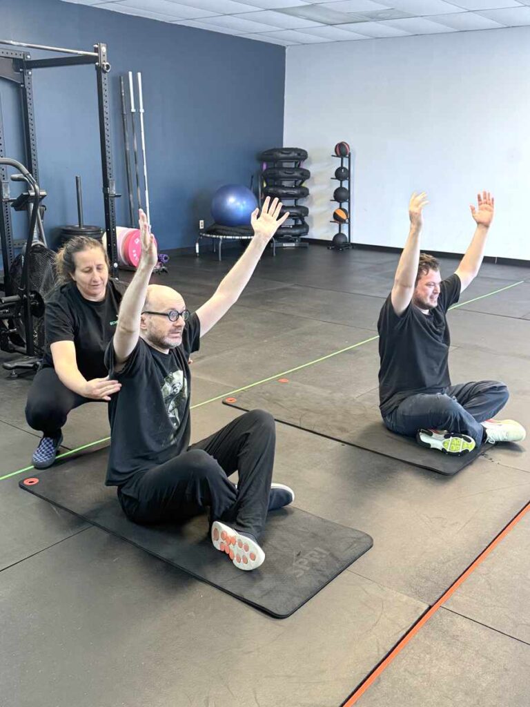 2 individuals doing yoga stretches with coach melissa