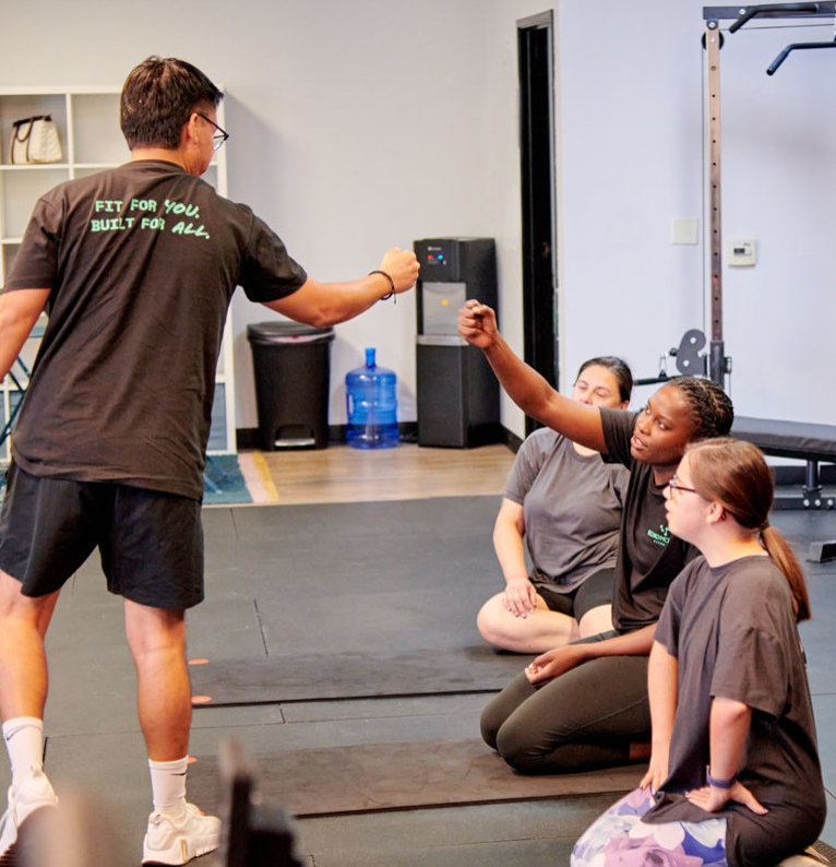 A coach fist-bumping athletes after a group class