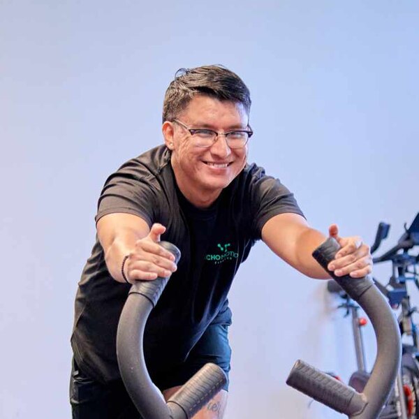 Rudy, Echo Motion Fitness coach, smiling on an air bike
