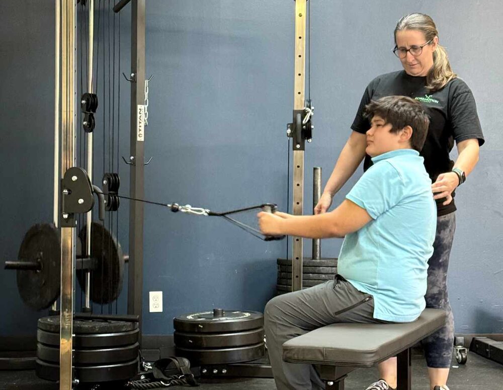 A coach guiding an athlete through a seated cable row
